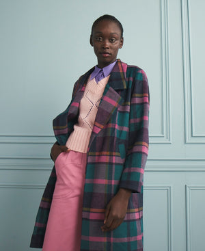 A model wearing a  Coat with a pink and green check pattern. The coat has a straight line body, open front, lapels, and angled pockets at the hip.