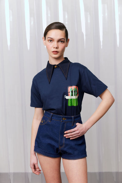Model wearing a navy blue outfit with a graphic design against a white curtain background