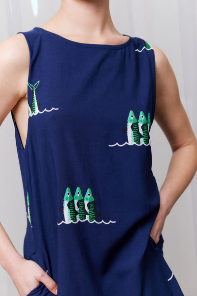 Navy blue sleeveless top with green fish patterns worn by a person against a plain background