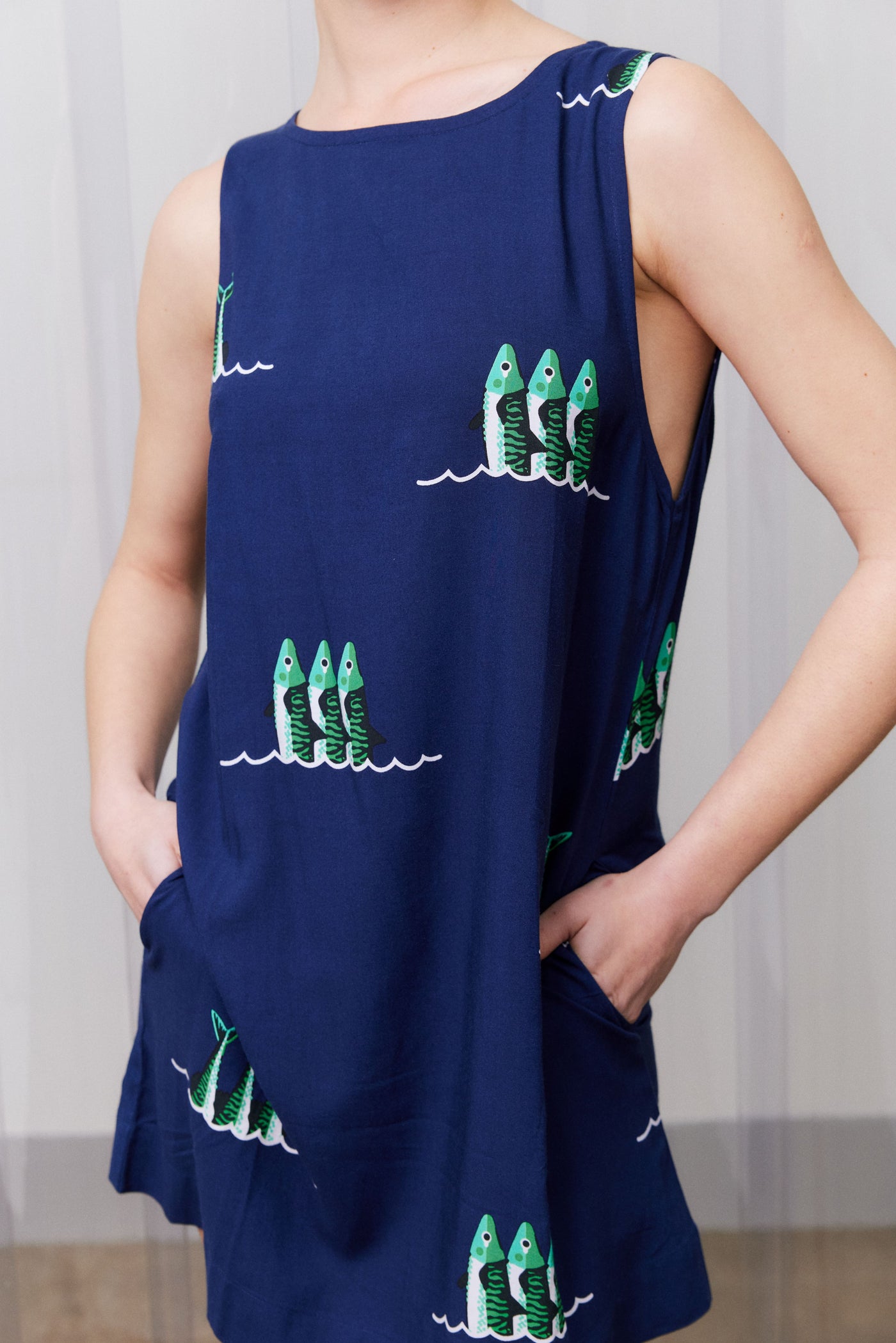 Navy blue dress with green fish patterns worn by a person against a neutral background