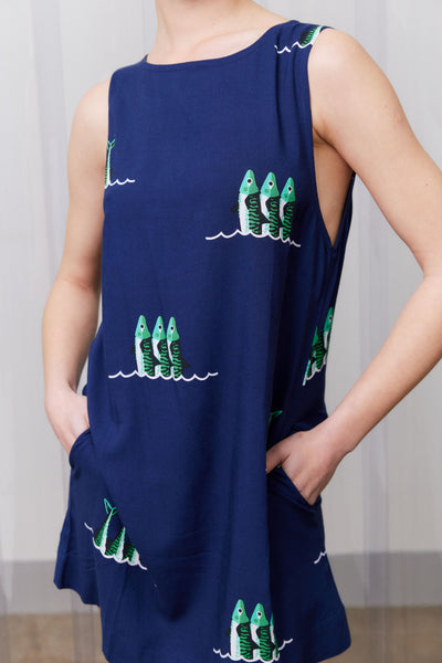 Navy blue dress with green fish patterns worn by a person against a neutral background