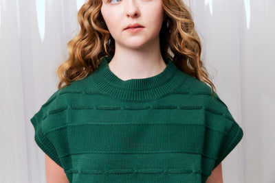 Woman wearing a green knitted top against a white background