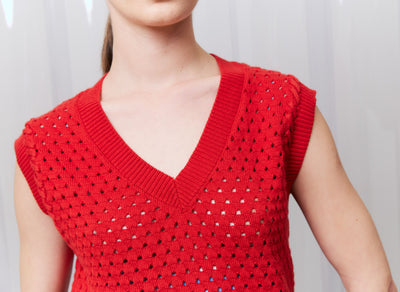 Red sleeveless knitted top worn by a person against a plain background