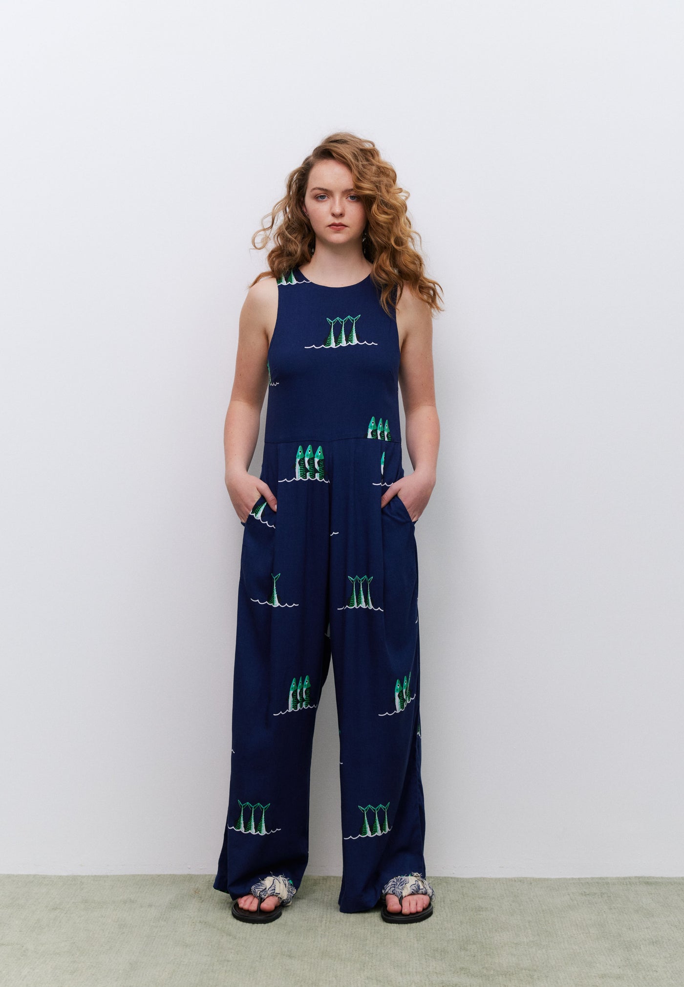 Woman wearing a navy blue jumpsuit with green patterns against a white background