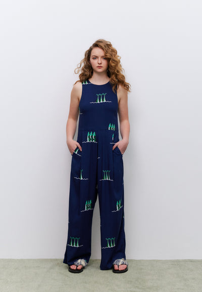 Woman wearing a navy blue jumpsuit with green patterns against a white background