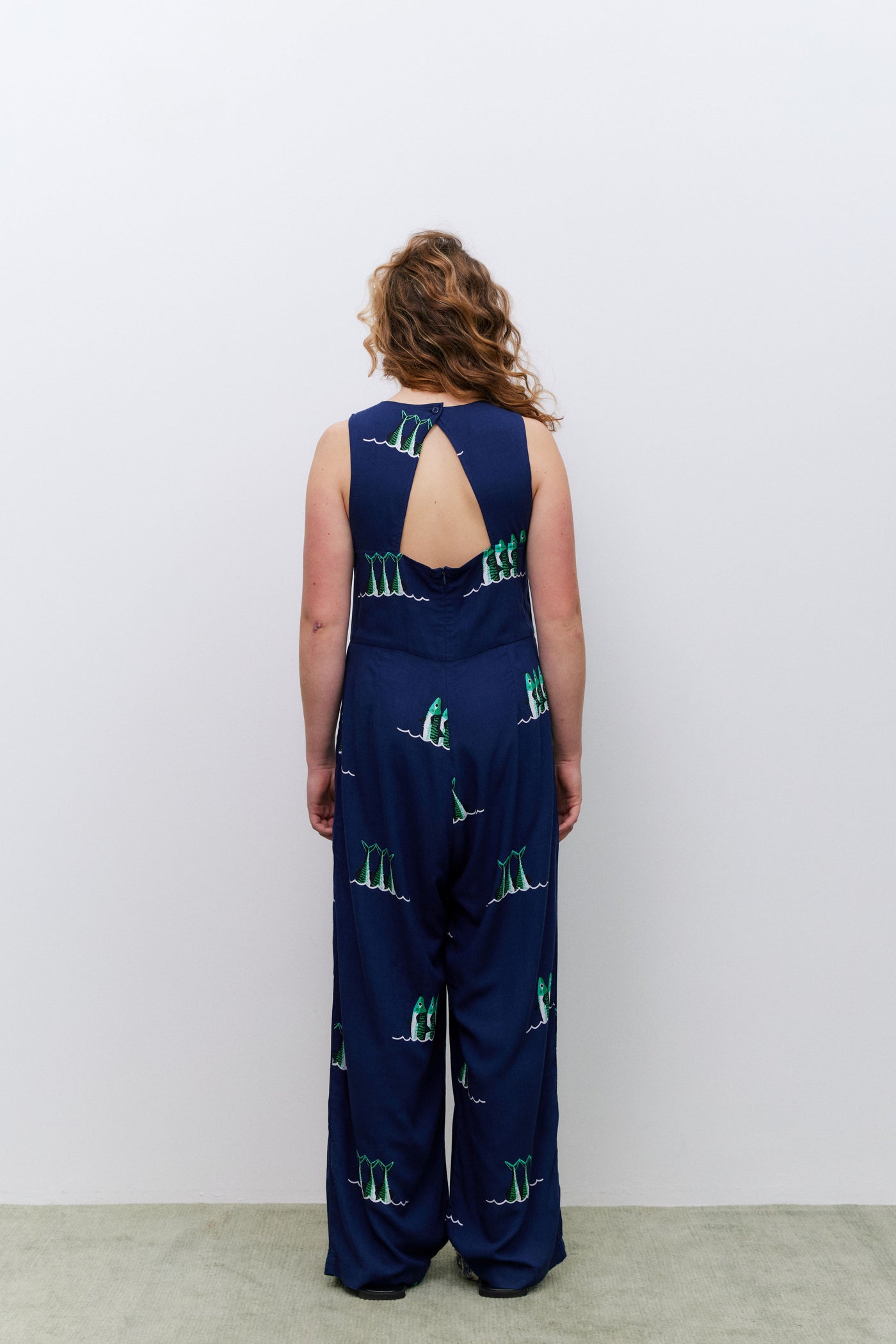 Person wearing a navy blue jumpsuit with green patterns on a white background
