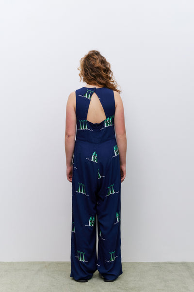 Person wearing a navy blue jumpsuit with green patterns on a white background