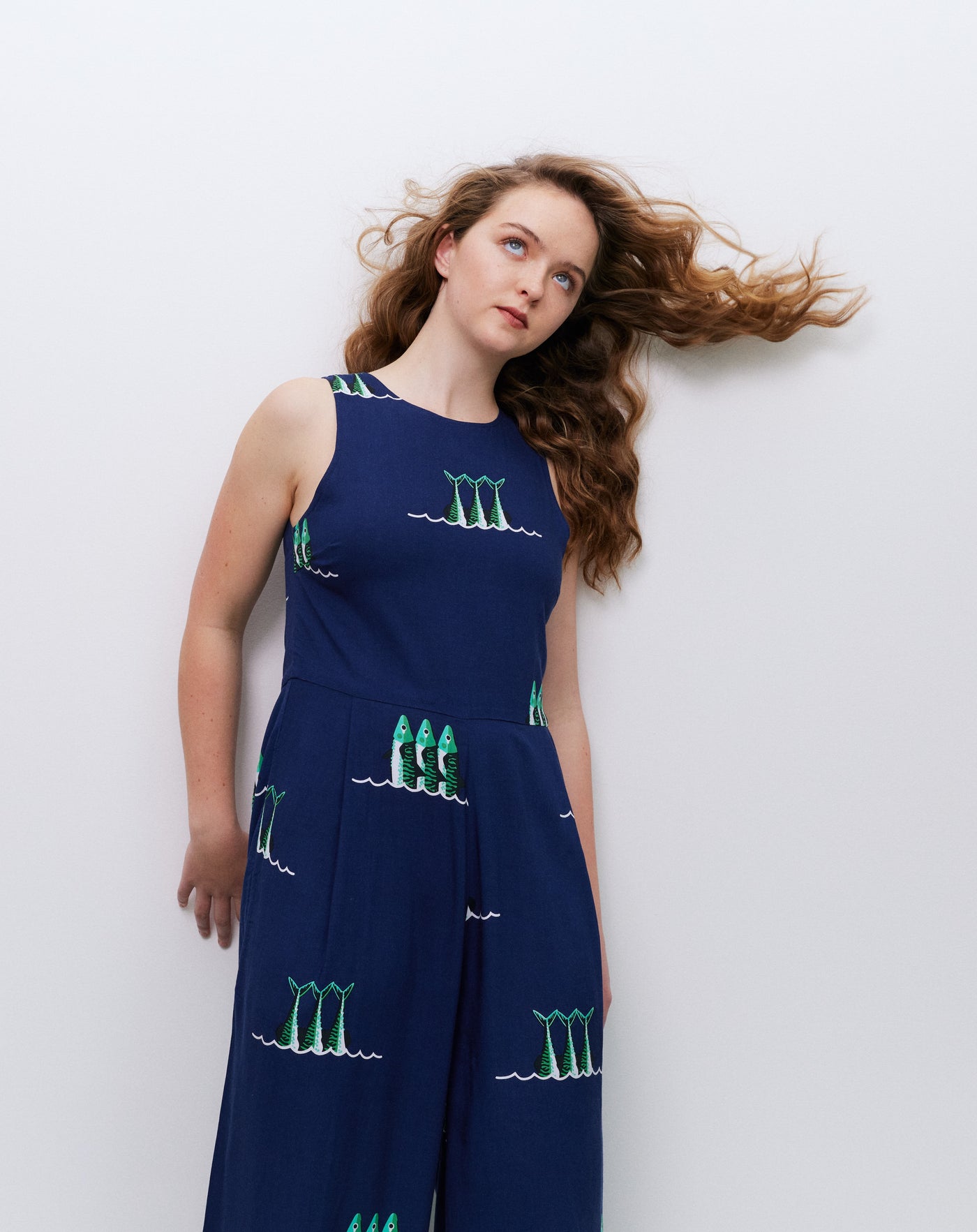 Woman wearing a navy jumpsuit with green patterns against a white background