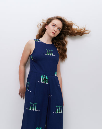 Woman wearing a navy jumpsuit with green patterns against a white background