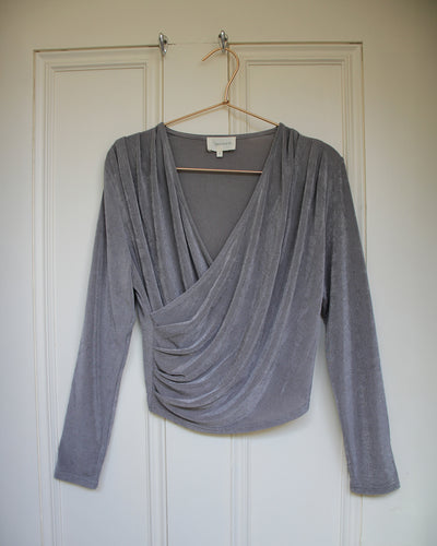 Gray draped top on a hanger against a white door background