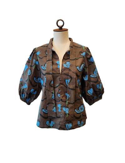 Brown blouse with blue floral pattern on a mannequin against a white background