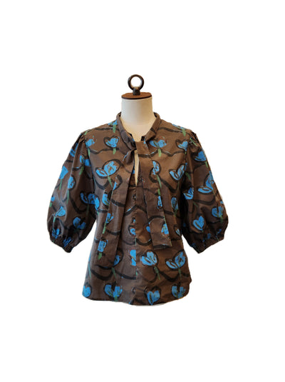Brown blouse with blue floral pattern on a mannequin against a white background