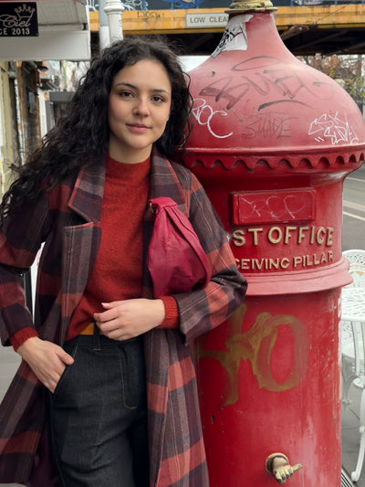 Woman standing next to a red post office pillar with graffiti