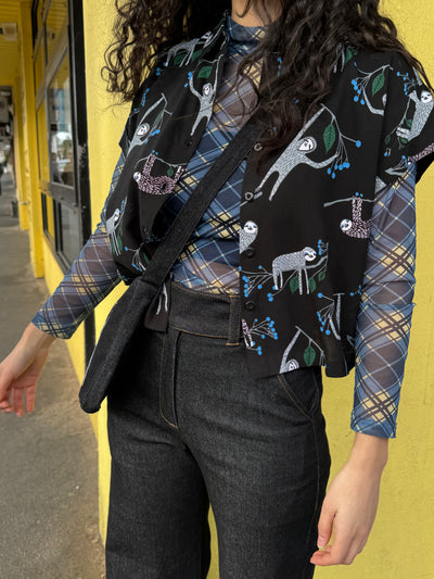 Person wearing a patterned shirt with plaid sleeves against a yellow wall.