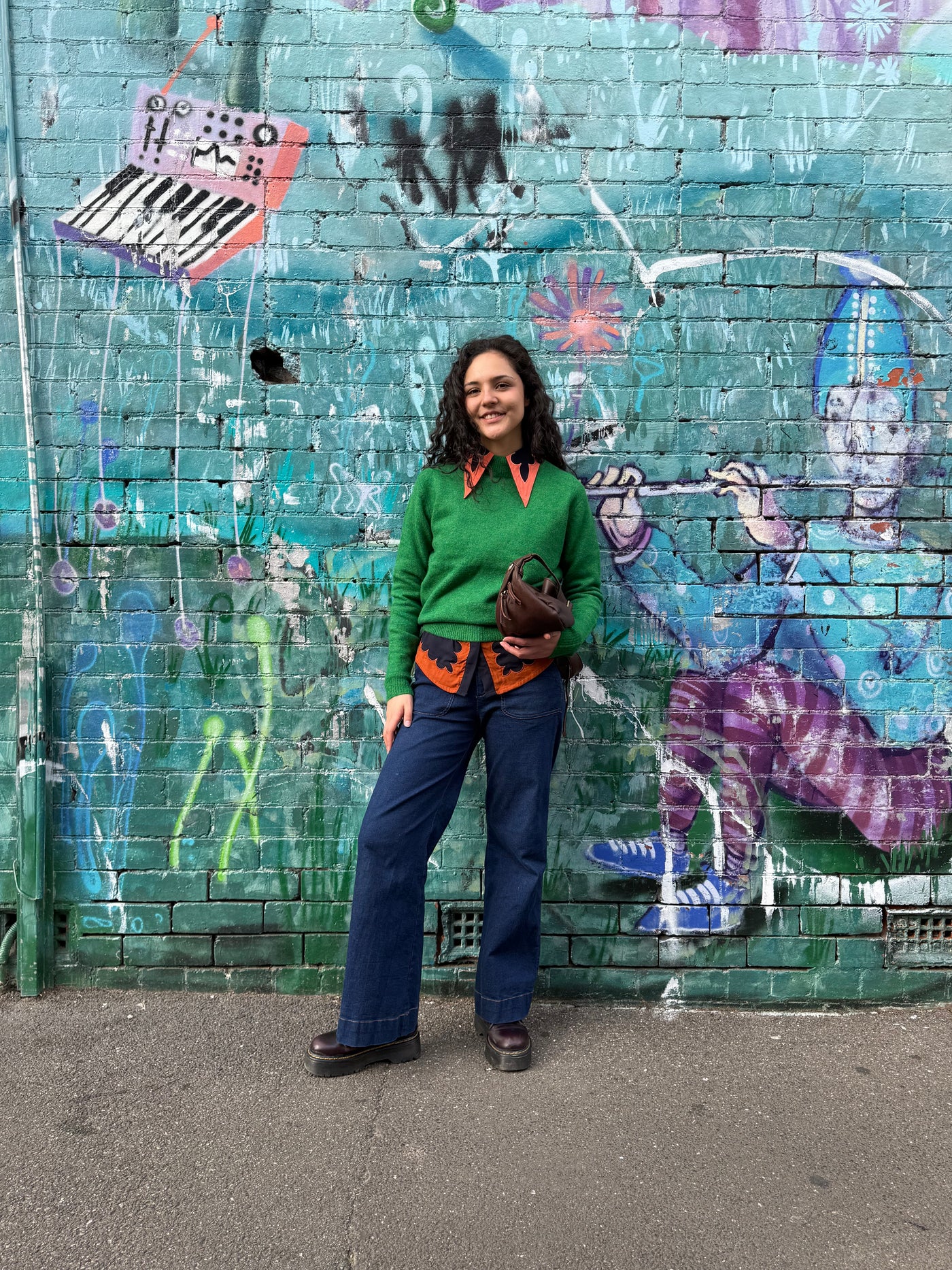 Person standing in front of a colorful graffiti-covered wall