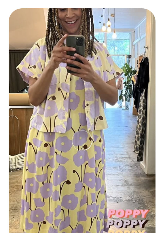 Person wearing a yellow poppy print dress under a matching shirt in a mirror selfie.