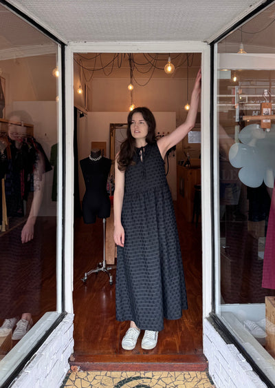 A girl in a doorway wearing a long black textured dress from Leonard St.