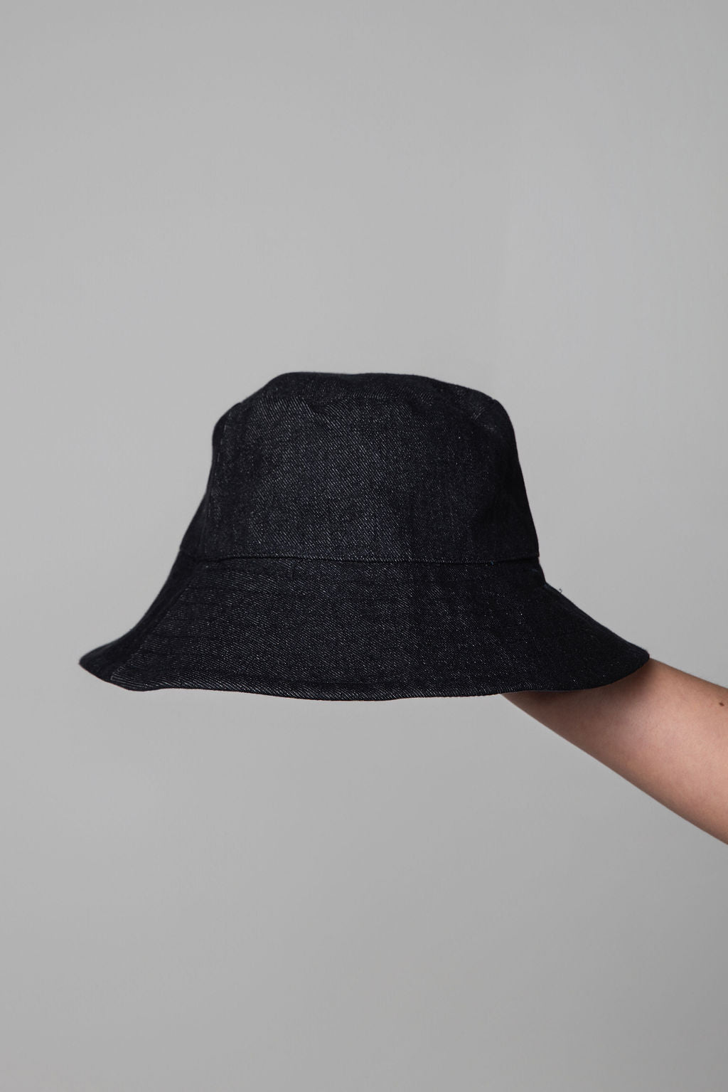 Black bucket hat held against a gray background