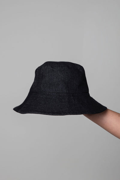 Black bucket hat held against a gray background