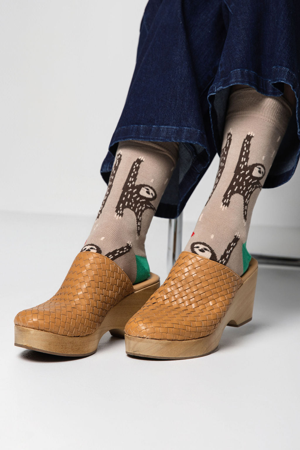 Person wearing beige socks with animal patterns and brown clogs on a light background