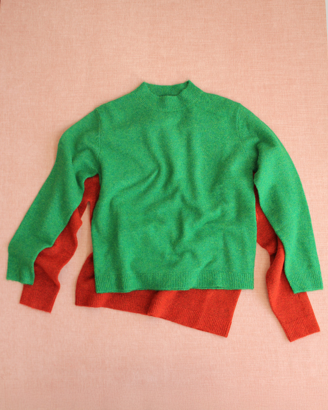 Green and red sweater on a pink background