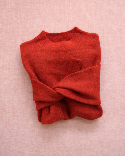 Folded red sweater on a pink background