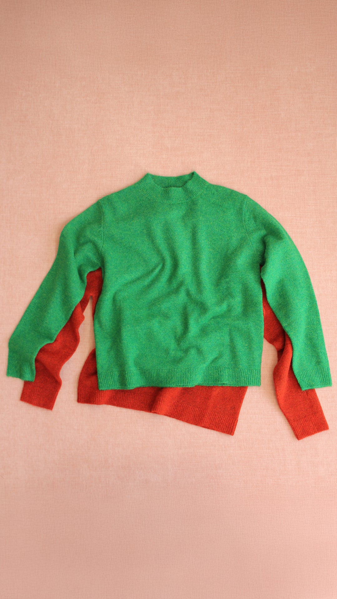 Green and red sweater on a pink background