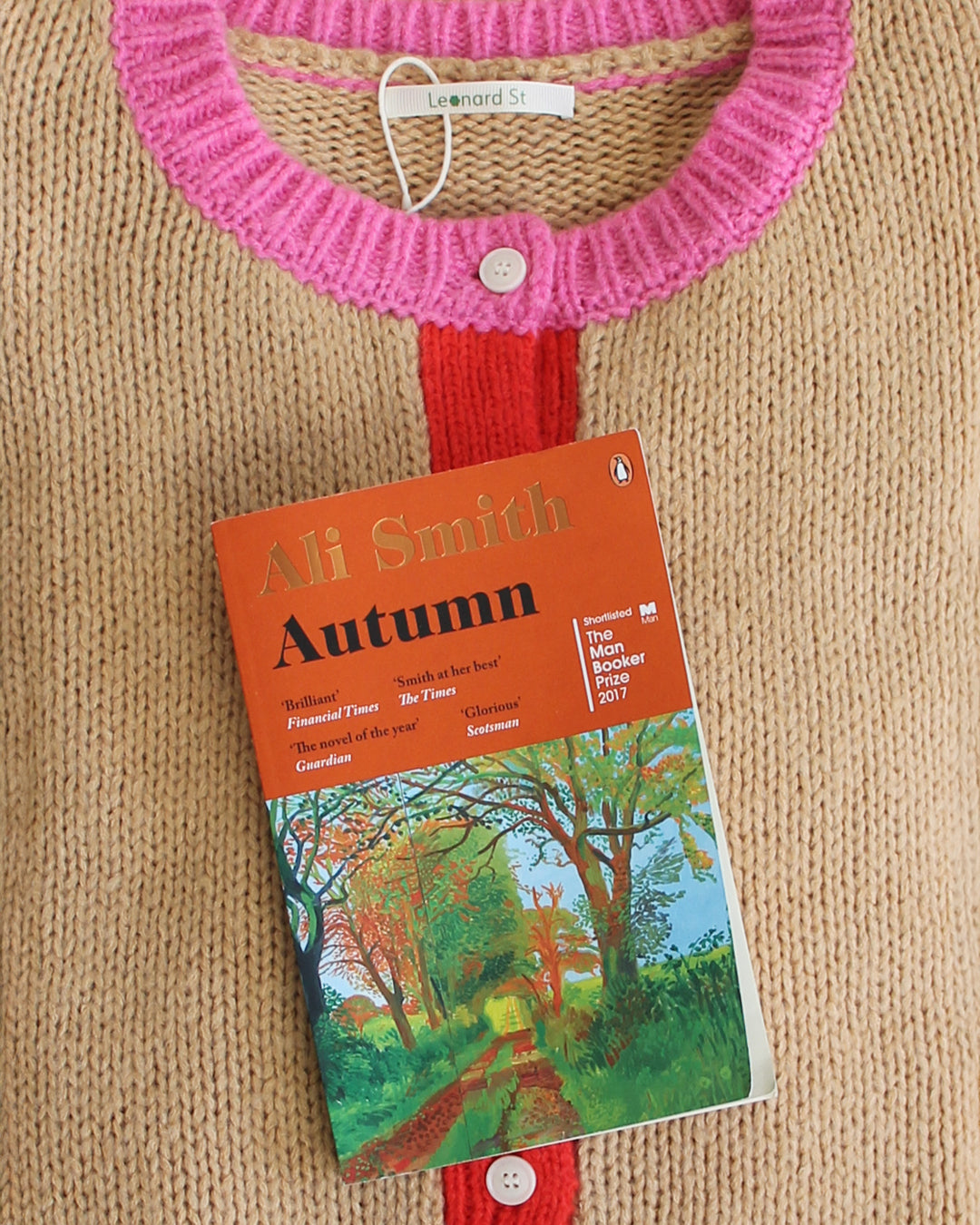Book titled 'Autumn' by Ali Smith with a pink and red holder cardigan background