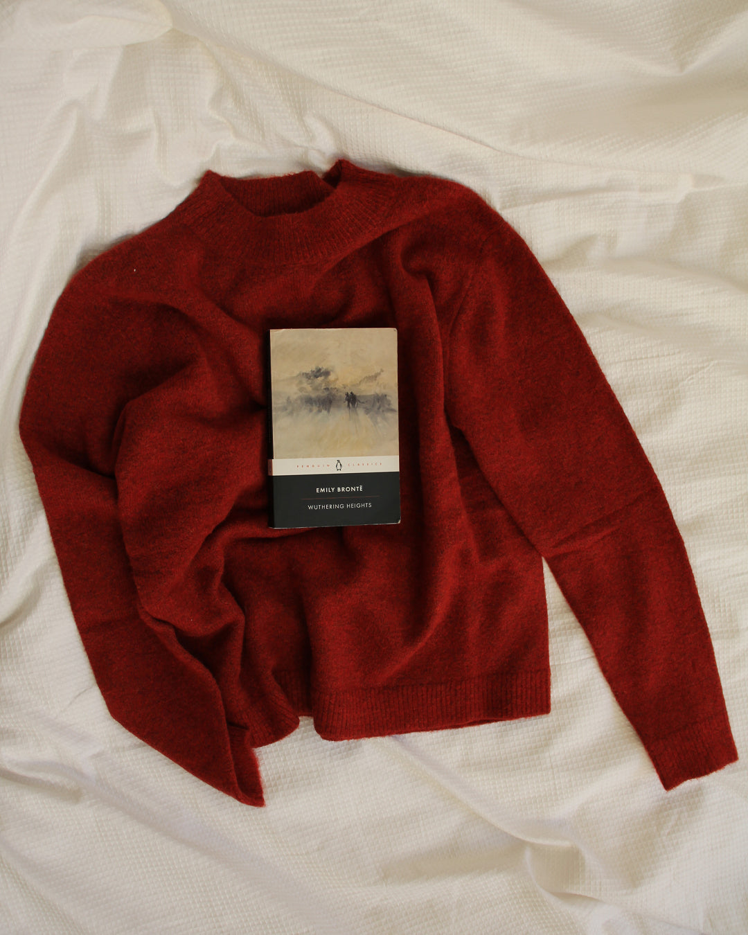 Red sweater with a book on a white fabric background