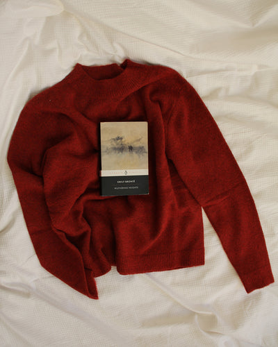 Red sweater with a book on a white fabric background