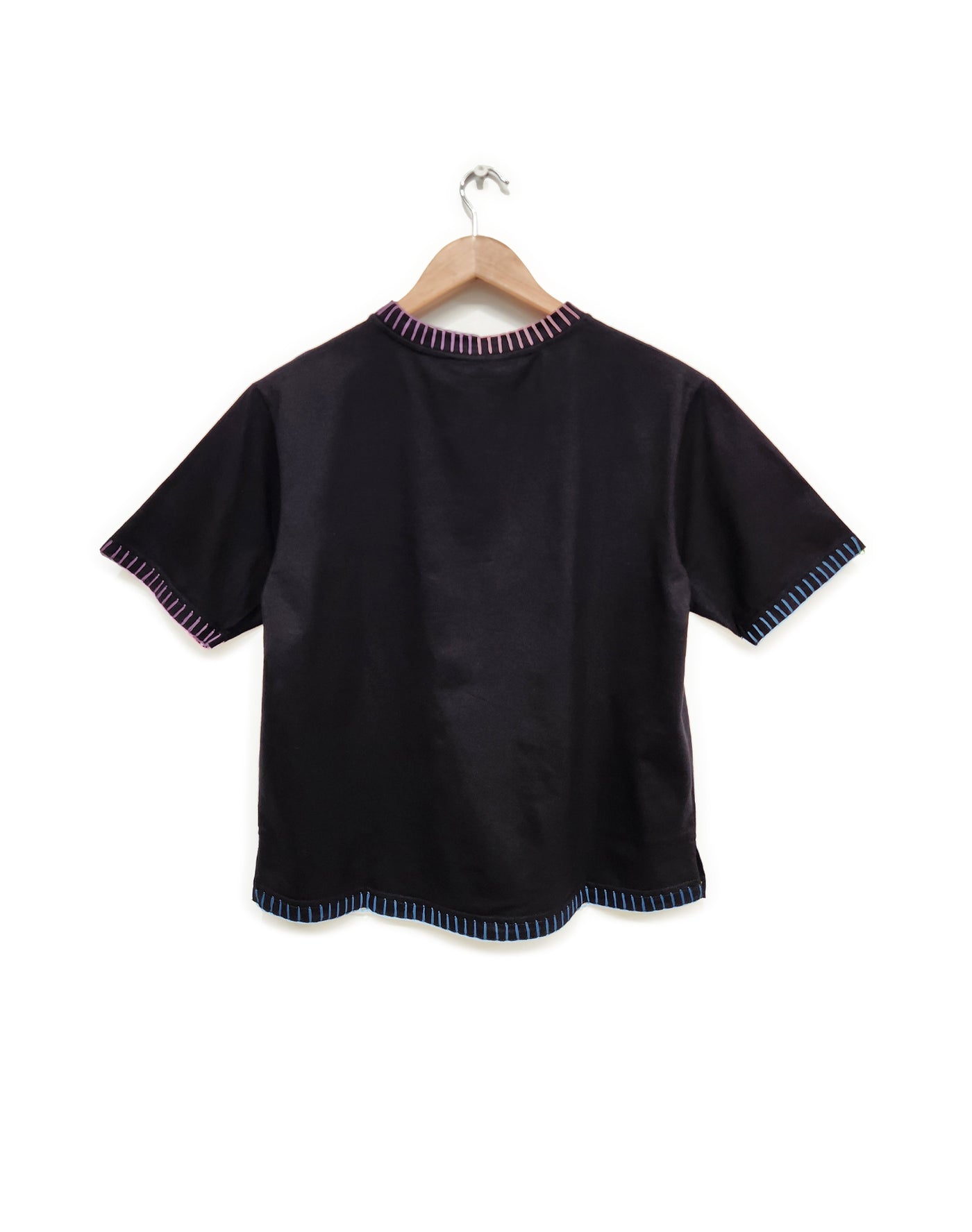 Black shirt with striped trim on a hanger against a white background