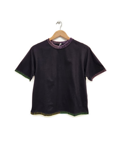 Black top with colorful trim on a hanger against a white background
