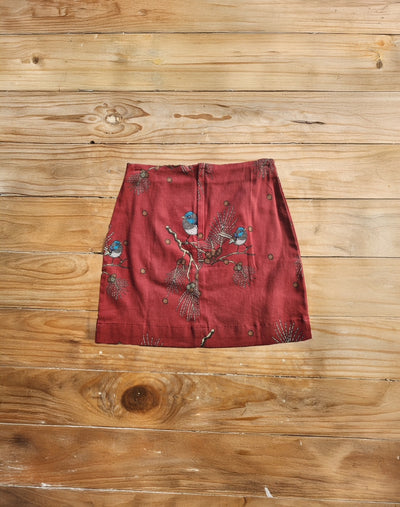 Red skirt with bird print on a wooden surface