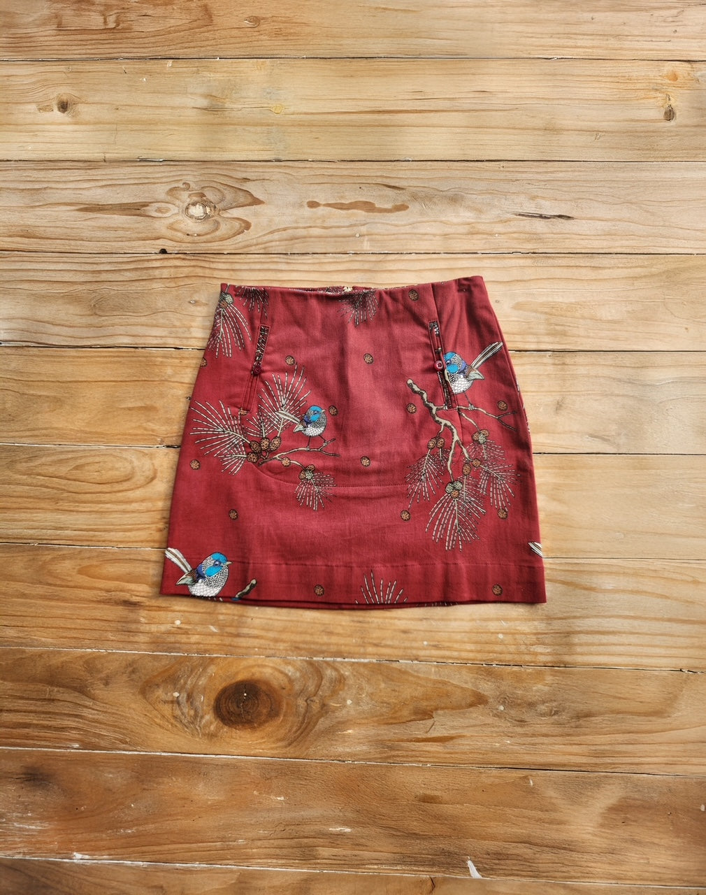 Red skirt with bird and floral print on a wooden surface